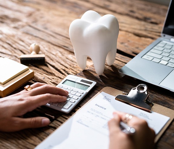 Patient calculating cost on desk with prop tooth